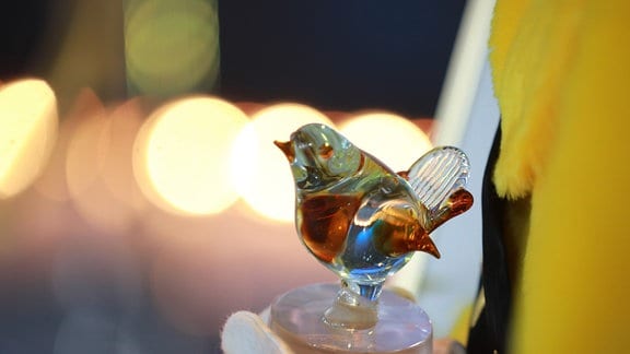 Zu sehen ist die Trophäe "Goldener Spatz", es ist eine Spatzen-Glasfigur auf einem kleinen Sockel.