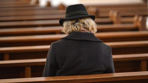 Eine einzelen Person sitzt in einer Kirche.