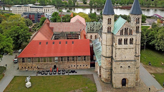 Das Kloster Unser Lieben Frauen in der Magdeburger Altstadt. Rechts das Kirchenschiff mit einem quadratischen Turm, flnakiert von zwei runden Türmen. Links daneben ein von alten Gemäuern umbauter Klosterhof.