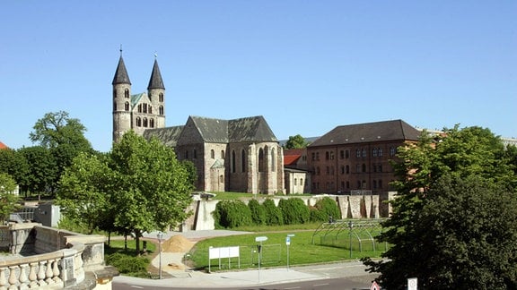 Ein Kloster in Magdeburg mit Kirchturm umgeben von Bäumen und Gebäuden