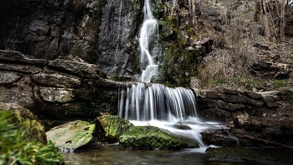 An einer Felswand fließt ein Wasserfall. 