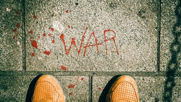 Das Wort WAR steht mit roter Farbe auf einem Fußweg
