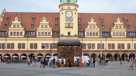 Menschen stehen um einen Kubus auf dem Marktplatz in Leipzig.