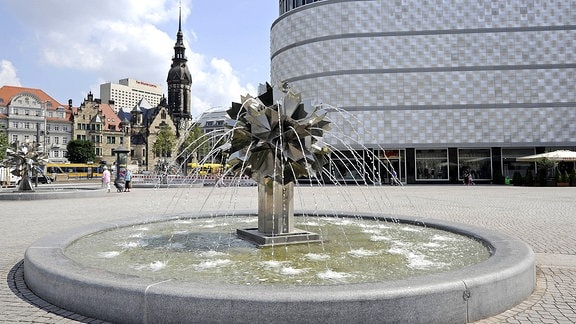 Der Richard-Wagner-Platz in Leipzig mit dem Springbrunnen Pusteblume von Bildhauer Harry Müller, dahinter die Höfe am Brühl