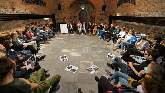 Veranstaltung beim Festival "Leipzig denkt", in einem Gewölbekeller sitzen zahlreiche Personen in einem Kreis.