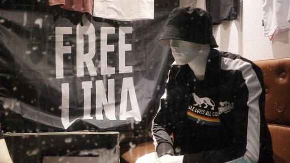Ein Transparent mit der Aufschrift „Free Lina“ hängt im Schaufenster eines szenetypischen Geschäftes im Stadtteil Connewitz