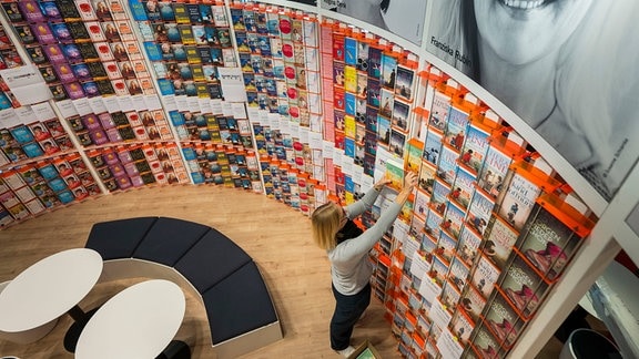 Eine Frau räumt Buecher am Stand von Droemer Knauer auf der Buchmesse