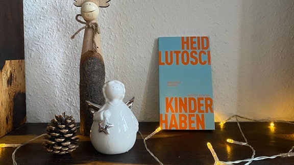 Das Buch "Kinderhaben" steht neben Weihnachtsdeko auf einem Schrank.