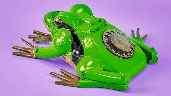 Laubfrosch-Skulptur vom Künstler Matthias Garff vor lilanem Hintergrund, hergestellt aus einem altem Telefon, das Ziffernblatt ist auf dem Rücken des Froschs zu erkennen.