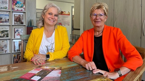 Das Bild zeigt zwei Frauen an einem Tisch: Sylvia Gramann (Bibliotheksleiterin) und Cornelia Schmädicke (Mitarbeiterin der Bibliothek und professionelle Märchenerzählerin), Organisatorinnen des Meininger Märchen- und Sagenfests.