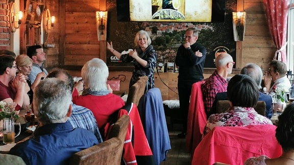 Aufnahme vom Märchen- und Sagenfest Meiningen 2023: eine Frau steht in einer rustikalen Gaststätte vor Publikum und erzählt eine Geschichte.