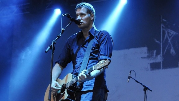 Sänger Marcus Wiebusch von der Band Kettcar auf einer blauen Bühne