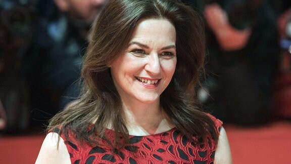 Martina Gedeck, eine Frau mit längeren Haaren lächelt.