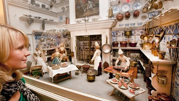 Eine Frau betrachtet im Schlossmuseum in Arnstadt den Schaukasten "Hofküche" aus der Puppensammlung "Mon Plaisir"