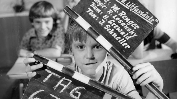 Schwarzweiß-Bild eines Jungen mit Filmklappe.