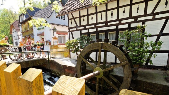 Besucher des Thüringer Mühltals in der Nähe von Eisenberg betrachten das Mühlrad der Pfarrmühle.