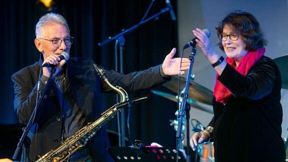Günther Fischer mit Saxophon und Uschi Brüning mit Gesangsmikrofon auf einer Bühne