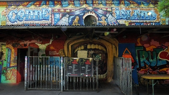 Eingangsbereich eines mit Graffiti übersähten Flachbaus 