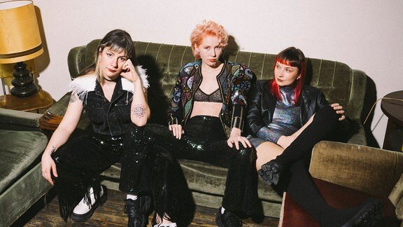 Die drei Bandmitglieder der Band My Ugly Clementine posieren auf einem Sofa.