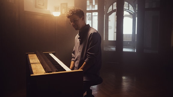 Sascha Stiehler sitzt am Piano. Die Bildstimmung ist Mystisch.