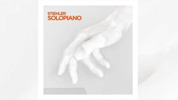 Das Albumcover der Platte "Solopiano" von Sascha Stiehler ist zu sehen. Eine weiße Hand ist zentral im Bild vor einem weißen Hintergrund.