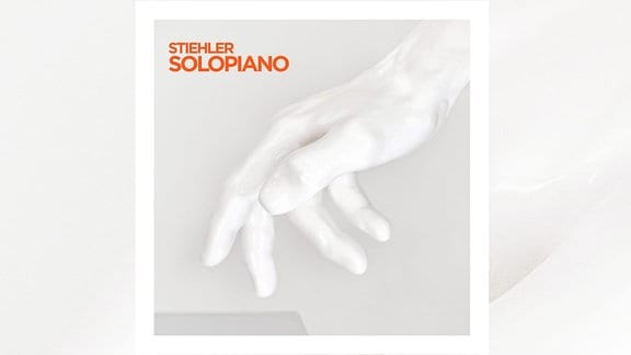 Das Albumcover der Platte "Solopiano" von Sascha Stiehler ist zu sehen. Eine weiße Hand ist zentral im Bild vor einem weißen Hintergrund.