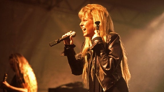 Sängerin Tamara Danz während eines Auftritts: sie trägt eine schwarze Lederjacke und singt ins Mikrofon