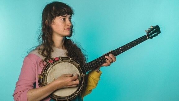Musikerin Kate Stables posiert mit einm Banjo in der Hand.