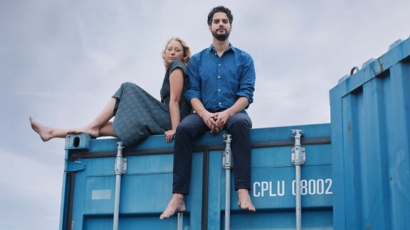 Julia und Raphael von der Band Toi et Moi sitzen auf einem Fracht-Container.