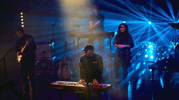Vier Musiker bei einem Konzert auf einer Bühne.