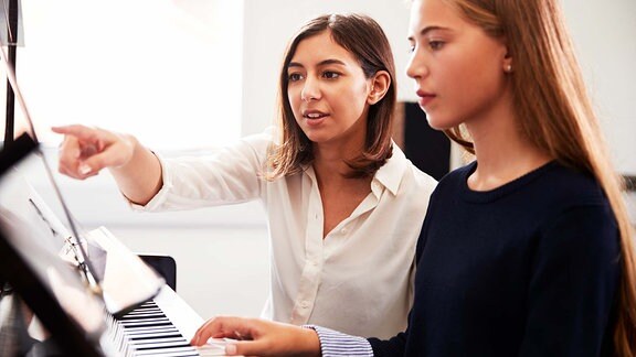 Zwei Mädchen spielen Klavier.