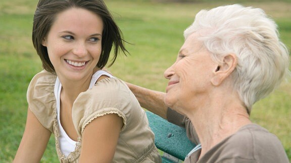 Eine jüngere und eine ältere Frau lächeln einander an