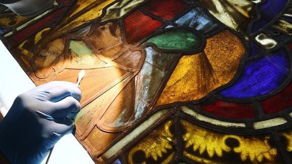 Eine Restauratorin arbeitet an einem Fenster mit der Figur der heiligen Maria Magdalena aus dem Naumburger Dom
