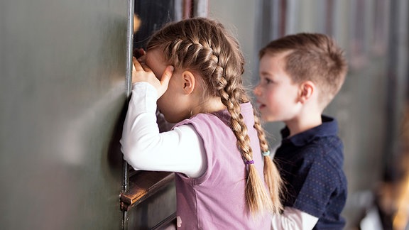 Zwei Kinder schauen durch die Fenster einer alten Lok.