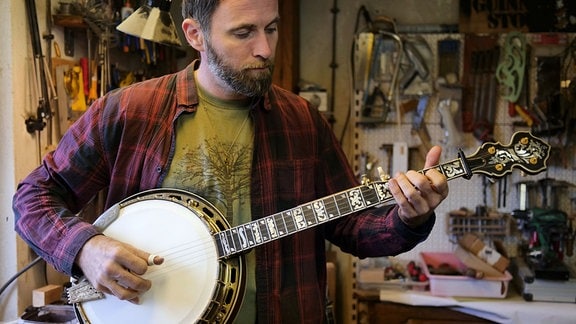 Nico Schneider spielt ein aufwendig hergestelltes 5-String Banjo mit Resonator, Perlmutteinlagen und reichen Schnitzereien