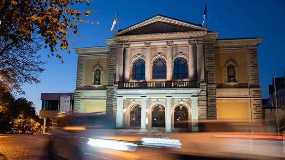 Oper Halle, Blick auf das Hauptportal aus Richtung Juliot Curie Platz,  blaue Stunde, Querformat, Herbst, Auto fährt vorbei