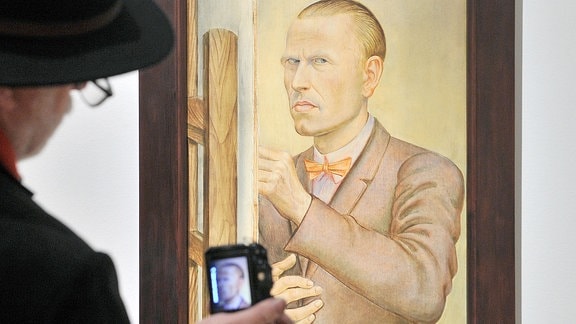 Ein Besucher fotografiert ein Selbstbildnis von Otto Dix.