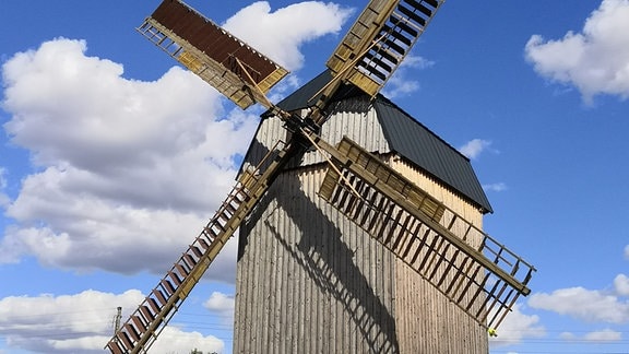 Eine Mühle mit Flügeln unter blauem Himmel