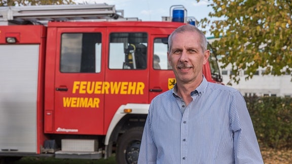 Feuerwehrmann Ralf Seeber vor einem Feuerwehrwagen.