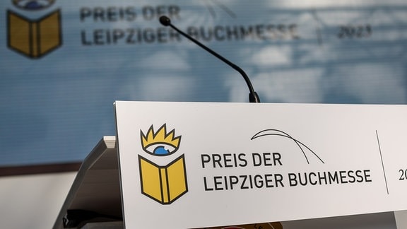 Ein Schild „Preis der Leipziger Buchmesse“ hängt vor der Preisverleihung an einem Rednerpult.