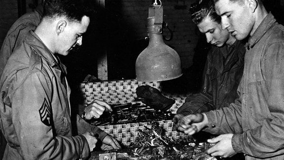 Anfang Mai 1945. Soldaten der 1. US Army untersuchen und sortieren Schmuck, Uhren und Brillen, die vom 6. DB der III. US Army bei der Freilassung des Konzentrationslagers Buchenwald gefunden wurden.