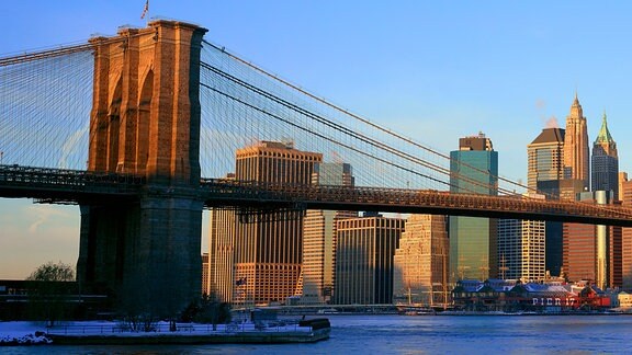 Brooklyn Bridge und East River bei Sonnenaufgang vor der Skyline von New York City