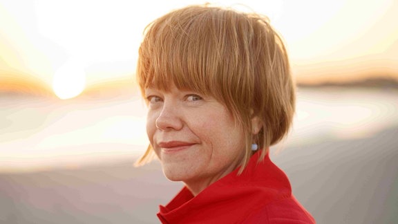 Randi Tytingvåg, eine Frau mit kurzen rötlichen Haaren, sie trägt einen roten Mantel. 