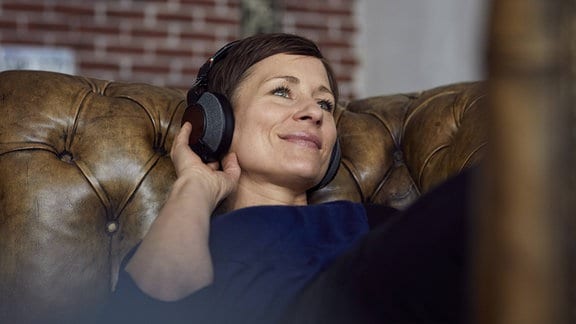 Musik hören - Frau mit Kopfhörer auf dem Sofa