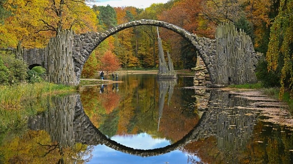 Die Rakotzbrücke im herbstlichen Azaleen- und Rhododendren-Park in Kromlau im Landkreis Görlitz nahe der Landesgrenze zu Brandenburg.