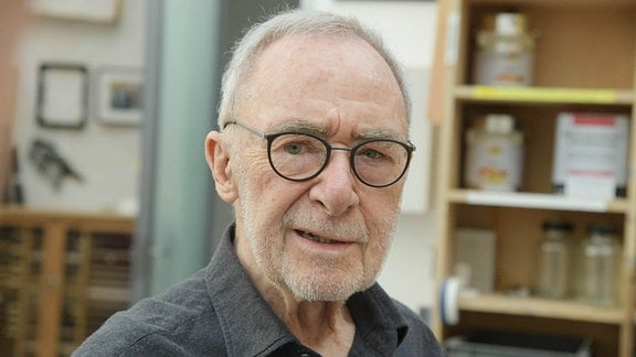Ein älterer Mann mit Brille in einem Atelier