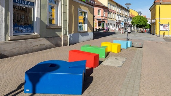 Bunte Sitzgelegenheiten in Form von Buchstaben sind in der Fußgängerzone Hauptstraße in der Innenstadt von Riesa, Sachsen.