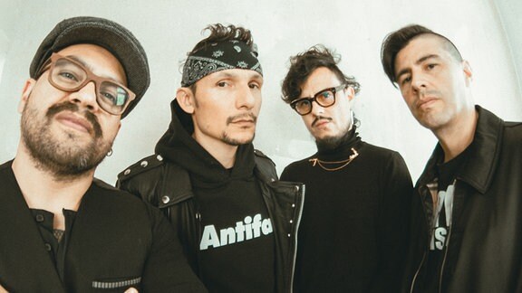 Der vier Musiker der Band Doctor Krápula in schwarzer Kleidung. Einer trägt einen Pullover mit der Aufschrift Antifa.