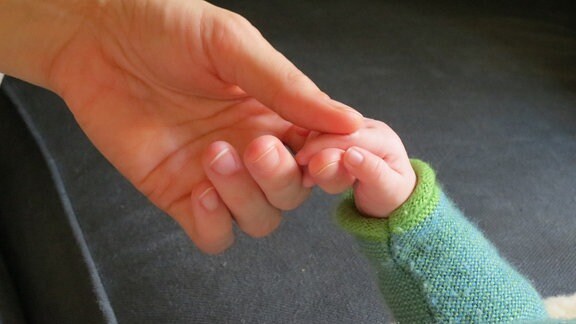 Hände von Baby und Hebamme