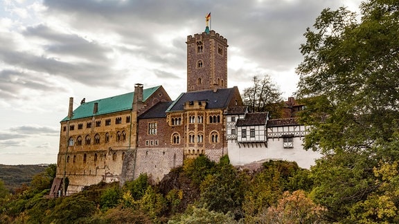 Die Wartburg über Eisenach im Thüringer Wald: ein Gebäude, das sichtbar aus mehreren Anbauten besteht, in der Mitte ein Turm